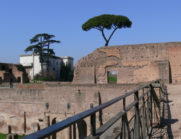 Photo taken from the top of the Palatine hill in Rome on a sunny spring morning. There are ancient Roman ruins in the foreground. Through a window in the ruins the Vatican is just visible in the distance.
